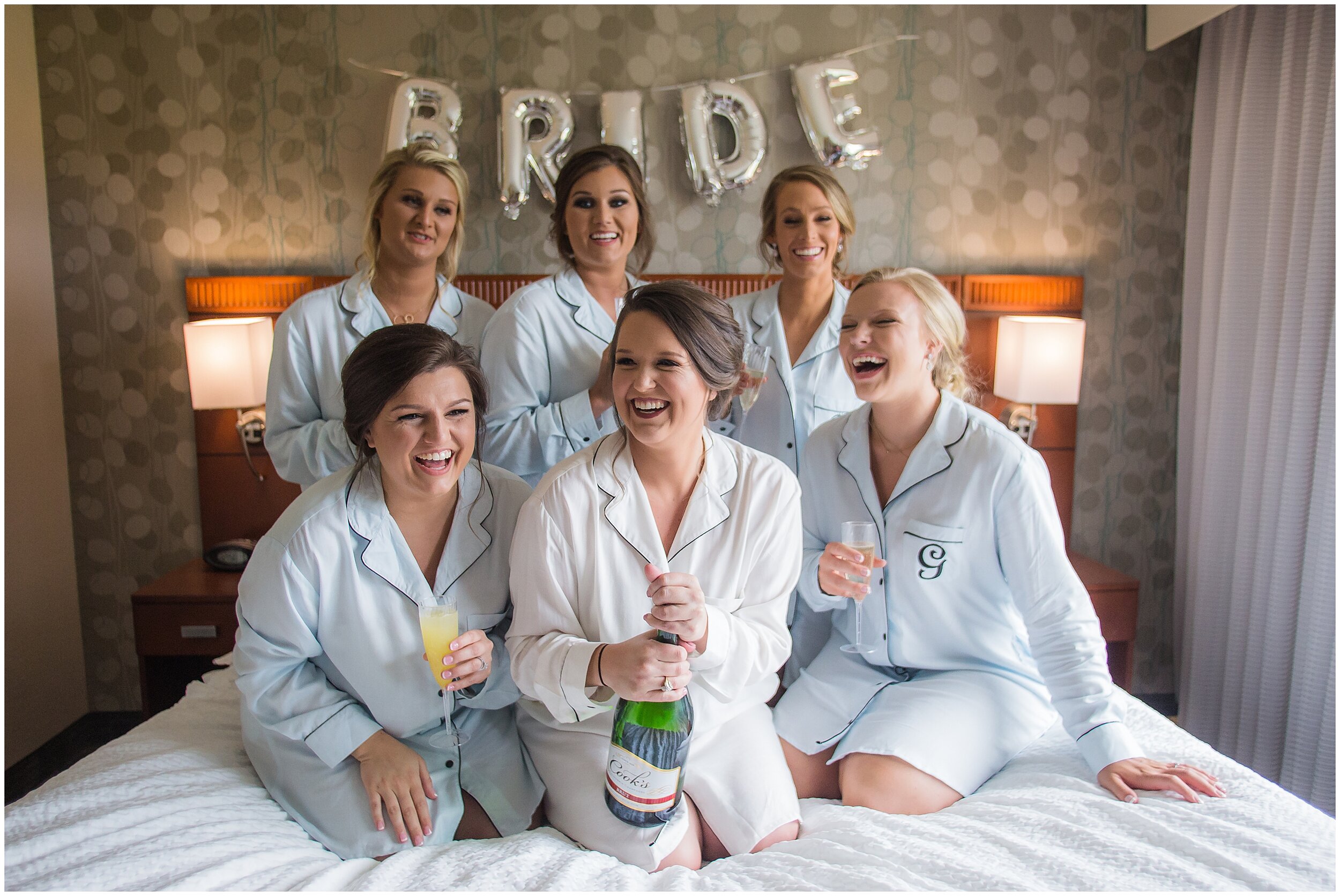 photo of bride holding champagne bottle surrounded by bridesmaids laughing on wedding day