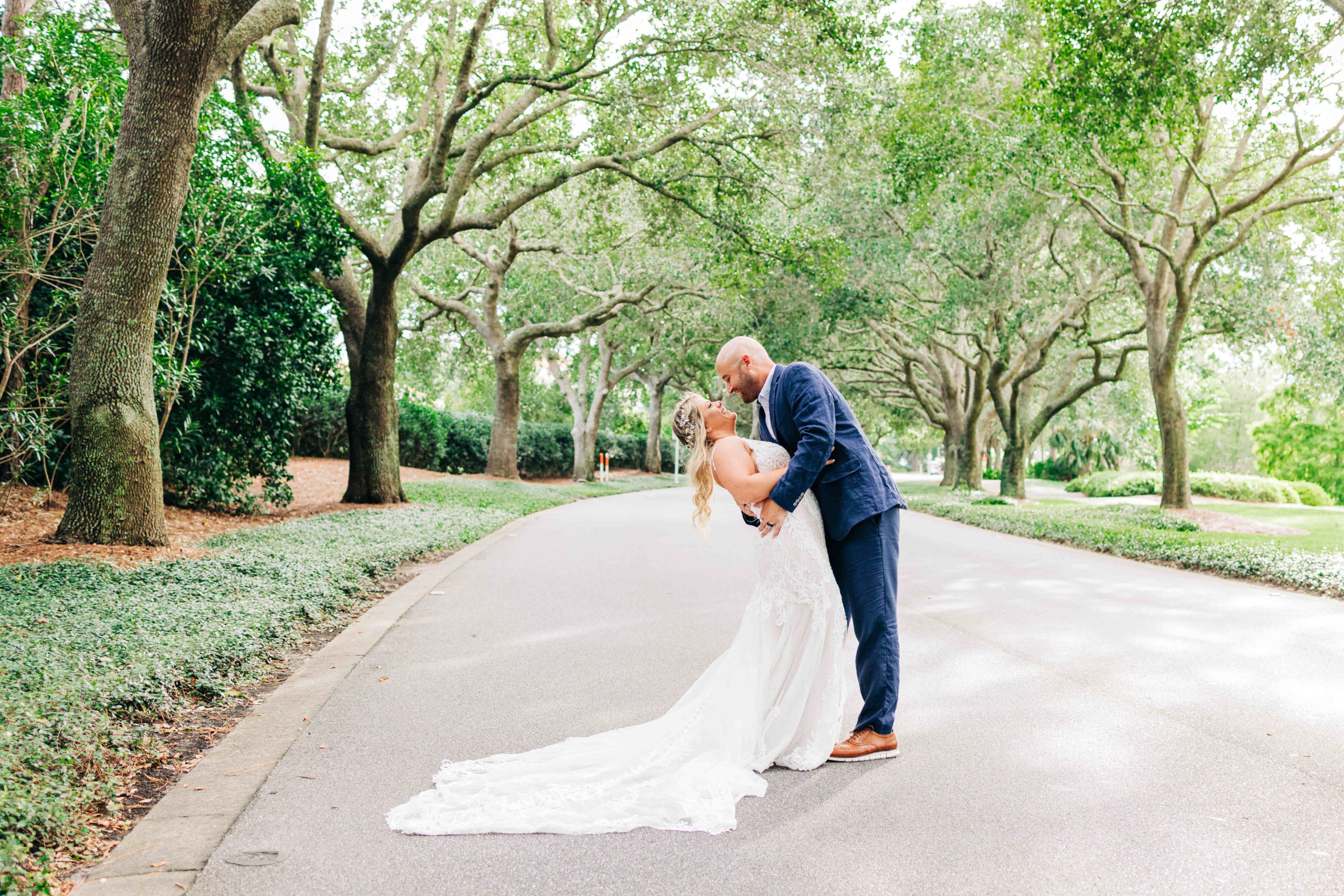 Groom dips bride in front of oak trees at Sandestin Resort in Destin Florida