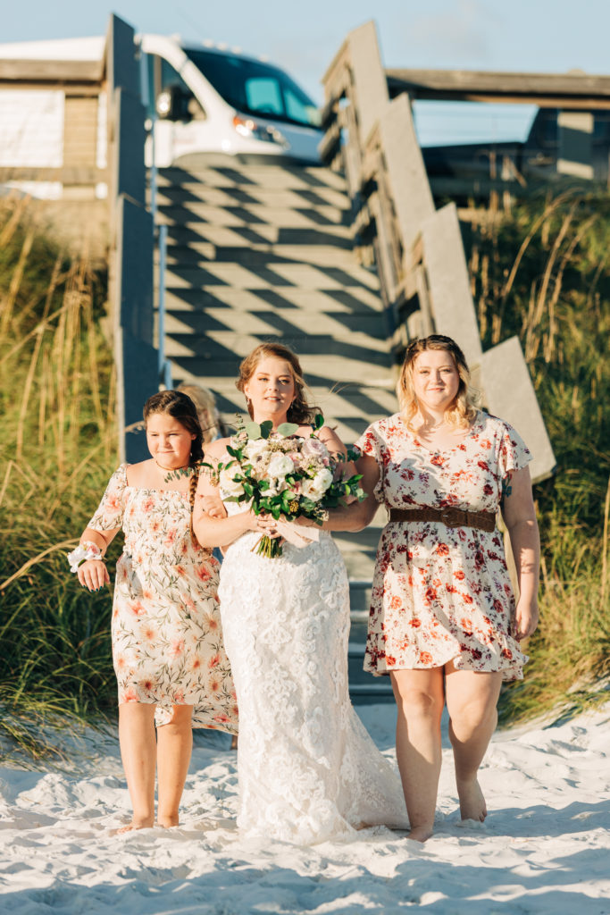 bride walks down her wedding aisle on Miramar Beach escorted by her two nieces