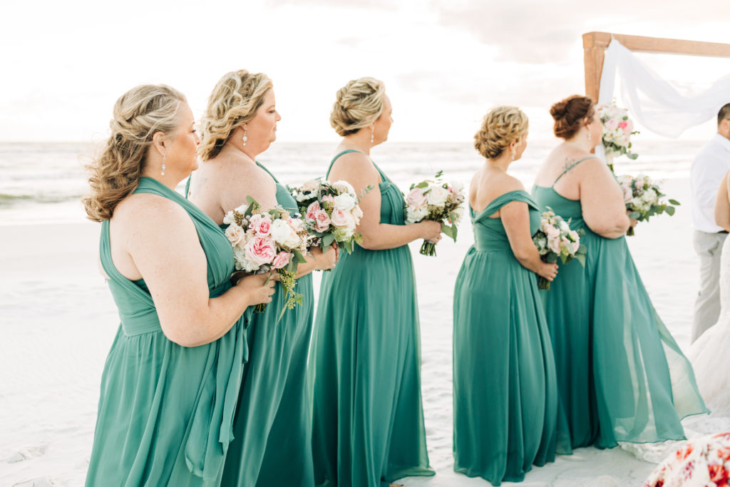 brides stand for ceremony in emerald green dresses