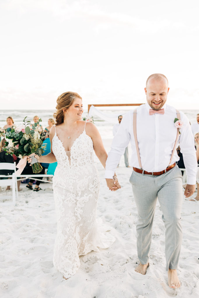 bride and groom smile as they walk down their ceremony recessional in Destin Florida