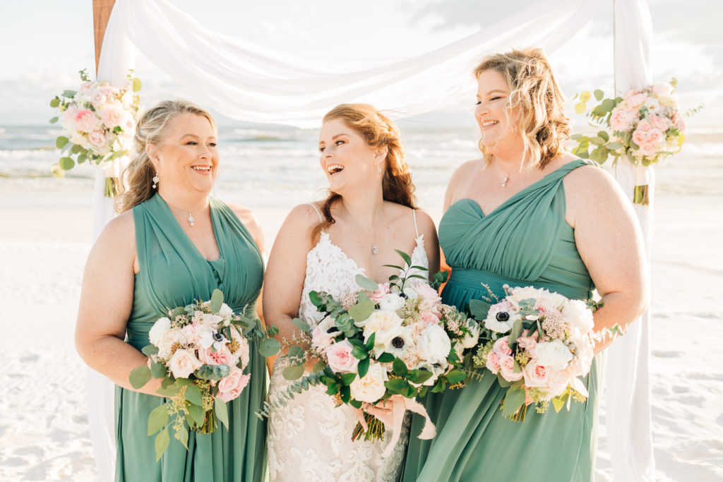 bride and her sisters laugh on Miramar Beach