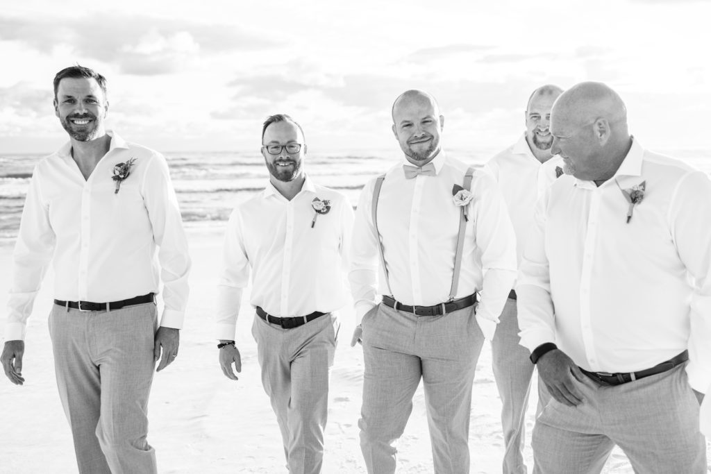 black and white photo of groom smiling surrounded by groomsmen on Miramar Beach