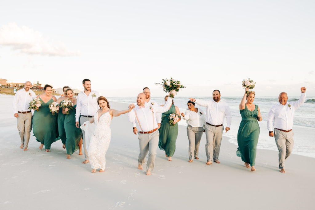 bride and groom and wedding party laugh and cheer on the beach in Destin Florida