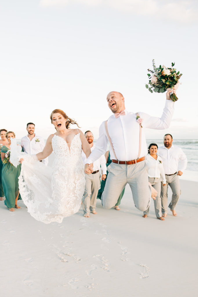 bride and groom jump for joy in wedding photos in Miramar Beach, Florida