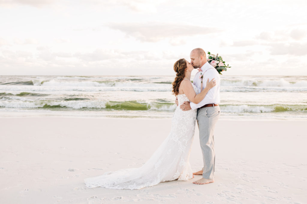 bride and groom kiss in front of the gulf on Miramar Beach Florida