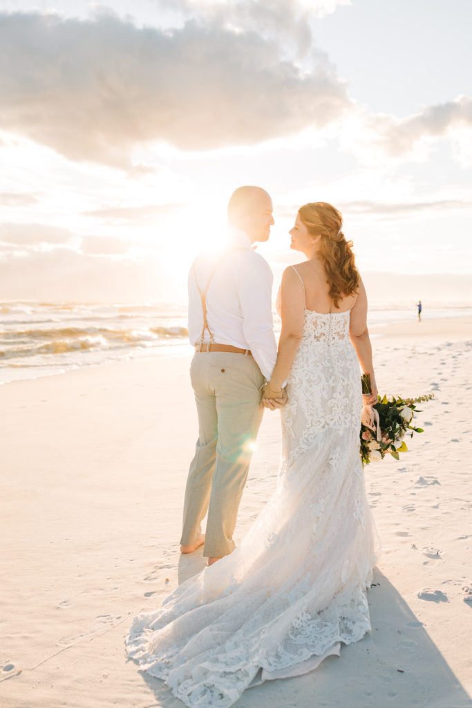 bride and groom pose for wedding portrait in front of sunset on Miramar Beach Florida