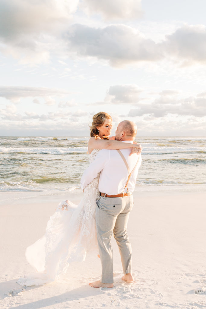Groom spins bride around by the gulf on Miramar Beach for wedding photo