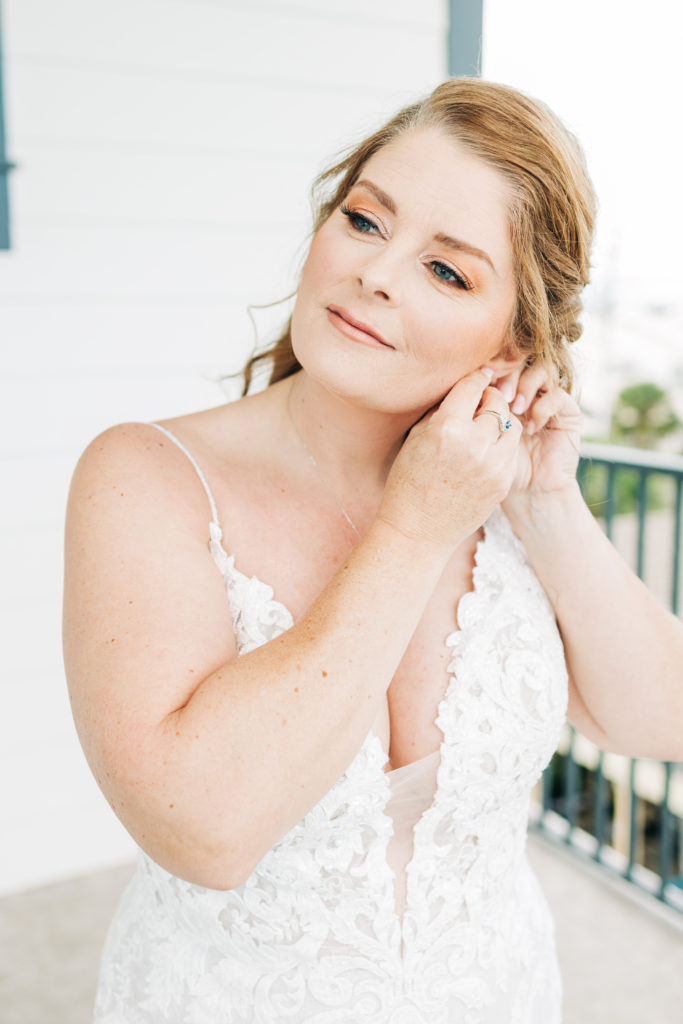 bride puts on her earrings for her wedding in Miramar Beach, Florida